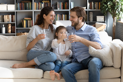 family drinking water on a couch at home