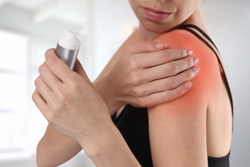 woman applying pain cream to shoulder