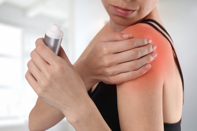 woman applying pain cream to shoulder